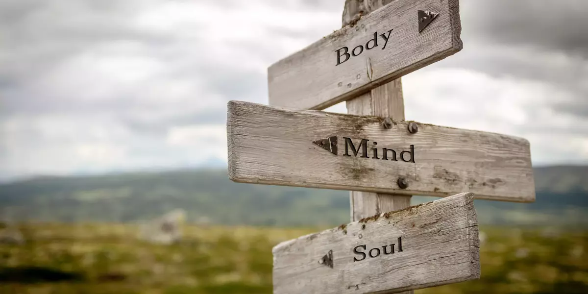 body mind soul text engraved on old wooden signpost outdoors in