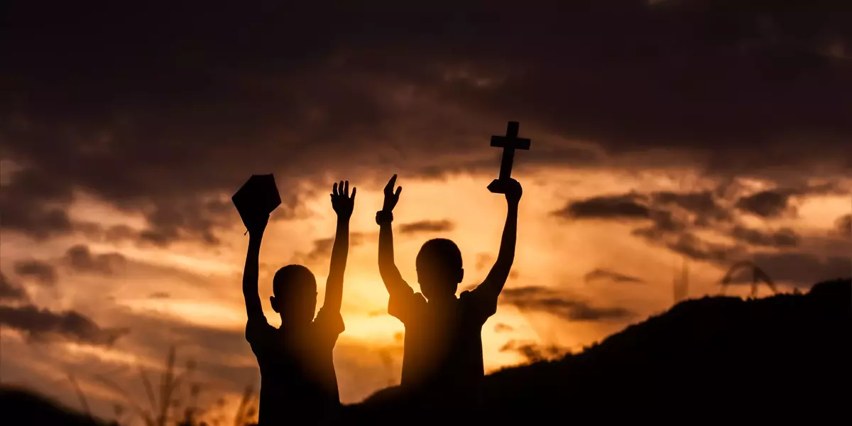 Two children worship God by holding christian Cross and Bible wi
